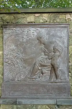 Bronze tablet of a woman handing a plant to a young boy