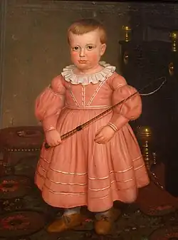 Niño estadounidense con vestido de color rosa antiguo, según la moda de 1840.
