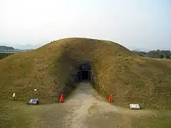 Pequeña loma, túmulo, con entrada al lugar de enterramiento.
