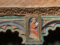 Monje joven rezando, entre los arquillos.