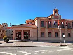Casa consistorial de Abades, sede de su ayuntamiento, al fondo la iglesia parroquial