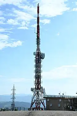 Torre de metal, blanca y roja, en la que se sujetan antenas blancas colocadas en diversas direcciones.