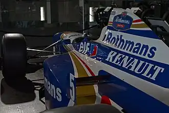 Primer plano desde el costado trasero de un monoplaza de carreras blanco y azul.