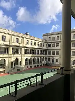 Patio interno de un edificio de tres y cuatro pisos, con una cancha de fútbol.