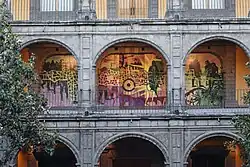 Un mural pintado en el pasillo con arcos arquitectónicos de un antiguo edificio.