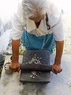 Tradicional molienda del frijol en metate.