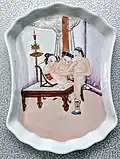 Un plato de porcelana china, c. 1900, que representa a un hombre que tiene relaciones sexuales con una mujer con los pies atados.
