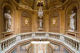 tres estatuas: Dante, Virgilio, Petrarca, escalera en el vestíbulo de entrada, parte superior.