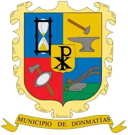 En el cuartel inferior izquierdo, sobre fondo rojo, el Hacha y la Batea catadora, en el escudo de Donmatías, Antioquia. Colombia.