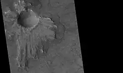 Cráter del pedestal, visto por HiRISE . La capa de eyección (asimétrica porque el asteroide llegó en un ángulo bajo desde el noreste) protegió el material subyacente de la erosión, por lo que el cráter parece elevado.