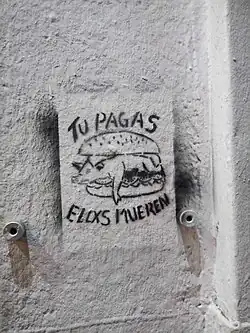 Esténcil con lema animalista ubicado en la comuna de Ñuñoa en Santiago de Chile, muestra un animal en un plato de comida y señala "tú pagas y ellos mueren"