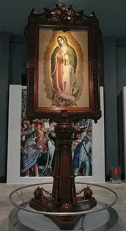 Estandarte de Hidalgo visto de frente en su marco y base, exhibido en la Sala de Banderas del Museo Nacional de Historia de México.