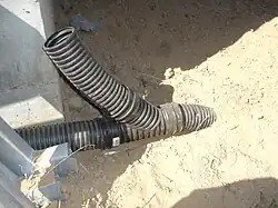 Un accesorio en Y que une una tubería corrugada perforada y no perforada a una salida sólida enterrada