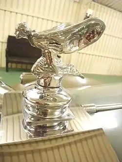 Versión arrodillada del Espíritu del Éxtasis, producida entre 1934 - 1939 y de nuevo entre 1946 - 1956. Este adorno de capó se montó en casi todos los Phantom IV. La estatuilla no está arrodillada en señal de respeto hacia los ocupantes como se ha afirmado en algunos artículos,[14]​[15]​ sino para facilitar una mejor visión al conductor del vehículo.[16]​ Chasis 4CS4.