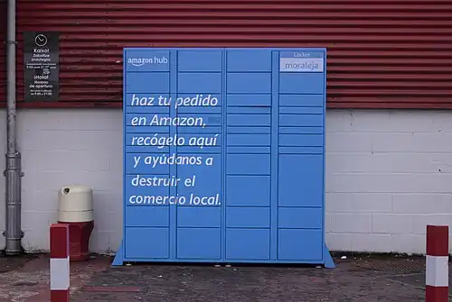 Alguien ha añadido un texto adicional a una taquilla de Amazon. "Compra en amazaon y ayudanos a destruir el comercia local."