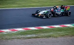 White, black and orange Formula One car turning left