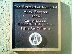 Placa del pedestal de la escultura del Haymarket Memorial. Nótese que el nombre del alcalde ha sido borrado y el sello de la ciudad cubierto con una a circulada