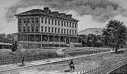 Imagen en blanco y negro de un edificio de tres pisos en un entorno rural.