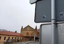 Dos de las pegatinas junto al campus de Segovia, al fondo, que piden la salida de los estudiantes de la ciudad. Estos adhesivos, fruto de la tensión social, están situados por toda la ciudad