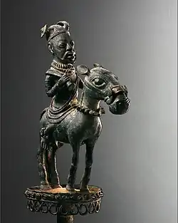 Copper alloy sceptre with horse-riding figure of a king or high-ranking noble of Ife, 12th –13th century CE. The vertical facial striation marks that typify early ife art is evident