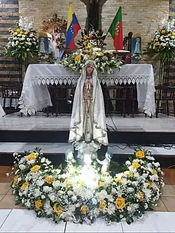 Iglesia de Nuestra Señora de la Luz, en Caracas, donde se venera a la Virgen de Fátima, acompañada por las banderas de Portugal y Venezuela al fondo.
