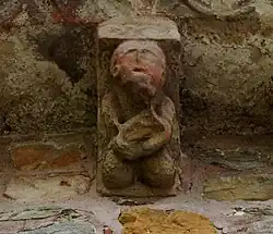 Canecillo que representa a un músico probablemente tocando la viola.