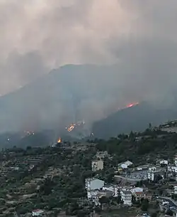 Incendio de Pedro Bernardo en 2022. Al fondo se encuentra el monte de la Abantera ardiendo y hay un humo negro y espeso. Delante se observan las últimas casas del pueblo