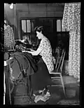Trabajadora de la N.M. Press Company (Nueva York) sentada ante una máquina de coser (1943).