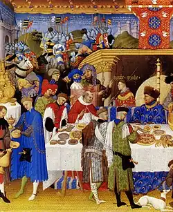 Ilustrando el calendario de Enero de Las muy ricas horas del duque de Berry (hermanos Limbourg, 1411-1416), se retrata al comitente en una escena profana, invitando a su mesa a sus allegados. Las paredes de la estancia están cubiertas de tapices que representan la Guerra de Troya.