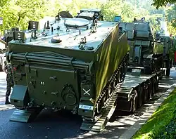 M-577A2 subiendo a una góndola de transporte