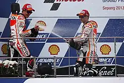 Marc Márquez y Dani Pedrosa celebran con champán la victoria en el Gran Premio de Malasia de Motociclismo de 2013.