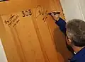 Respetando la tradición, Pontes firma la puerta del hotel de cosmonautas en Baikonour previo a su vuelo.