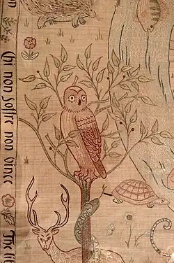 un buho bordado en rojo sobre fondo neutro con un ciervo, una tortuga...