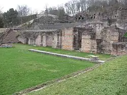 Remanente del pórtico con su estilóbato y una base de columna. El pavimento del pórtico está cubierto con un césped protector.