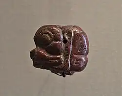 Cabeza de Pazuzu en piedra roja con inscripción. Museo del Louvre.