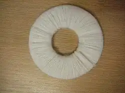 El hilo debe pasar numerosas veces por el agujero central. Cuanto mayor cantidad de pasadas se realicen mayor consistencia tendrá el pompón.