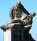 Soldado sujetando a un compañero caído, a la izquierda del monumento