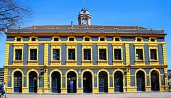 Fachada moderna de color azul y amarillo con aspecto de estación ferroviaria grande.