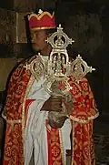Sacerdote de la iglesia de Yemrehanna Krestos[7]​ con vestiduras litúrgicas, portando una cruz.
