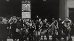 Una docena de mujeres posan para una fotografía en indumentarias variopintas.