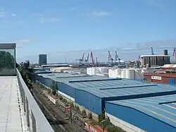 Vista general del interior del puerto de Bilbao con edificios de procesamiento de mercancías. Se puede ver un tren de mercancías en la triple vía.