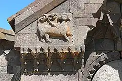 Altorrelieve de un animal alado a la izquierda y por encima de la entrada