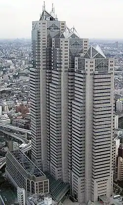 Aerial view of a beige high-rise lined with rows of windows; the building is composed of three adjoined towers of differing heights