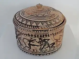 Píxide de finales del periodo geométrico, con escena probablemente inspirada en la guerra de Troya.