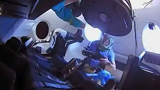 Miembros de la Expedición 58 ingresan al Dragon 2 por primera vez. Están usando equipo de protección para evitar respirar partículas que pueden haberse soltado durante el lanzamiento.