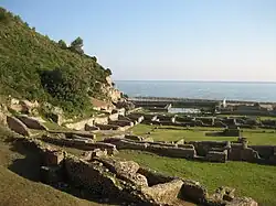 Primeiro plano dos restos do quartel e estábulos, no seu fundo a piscina e o triclínio.
