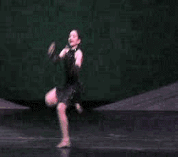 Una danzarina acrobática realizando un salto con split a horcajadas.