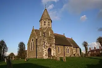 Iglesia de San Juan Bautista (1872), High Toynton, Lincolnshire, que muestra la inusual torre del porche suroeste con broches hasta el piso superior octogonal y rematada por una pequeña aguja[57]​