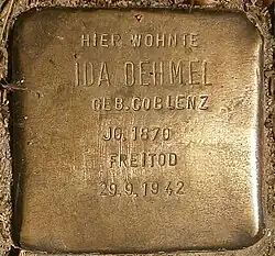 Primer plano del Stolpersteine o piedra de tropiezo hecha en lo que parece bronce y en la que se puede leer: «Hier wohnte Ida Dehmel Geb. Coblenz. JG. 1870 Freitod. 29/9/1942