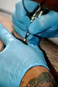 Realizando un tatuaje con guantes de látex